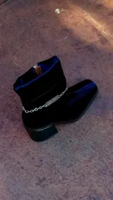 Bota de caña baja color marrón de terciopelo con efecto abullonado y cadena desmontable con el logo de la marca.