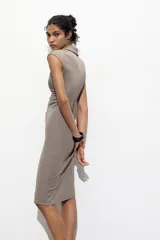 Vestido midi color gris topo, de cuello camisero y escote pico con manga corta. Tiene detalle de drapeado lateral y cierre frontal con botones metálicos.