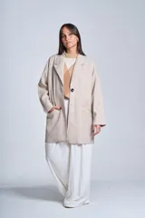 Tapado gris oscuro de corte oversize, con solapa clásica, hombros caídos, cierre con un botón central y bolsillos laterales funcionales.