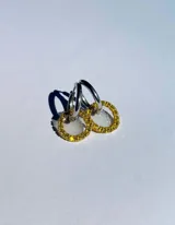 Par de aros colgantes con argollas doradas y dijes circulares de resina transparente con incrustaciones de strass de colores. El dije mide aproximadamente 1.5cm de diámetro.