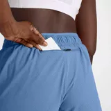 Short deportivo New Balance RC color celeste, con cintura elástica y cordón ajustable. Cuenta con tecnología NB DRY de secado rápido, malla interior sin costuras, bolsillo trasero con cremallera y detalles reflectantes.