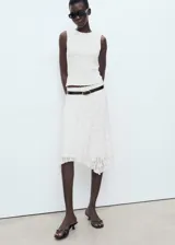 Falda midi de encaje blanco con diseño recto y bajo asimétrico con terminaciones en pico. Posee forro interior y cintura elástica.