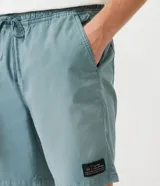 Bermuda celeste de sarga con cintura elástica ajustable con cordón, bolsillos laterales y traseros, y etiqueta con logo en la parte inferior.