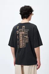 Remera negra de corte amplio con mangas cortas y cuello redondo. Presenta un pequeño estampado rectangular en el pecho y un estampado grande en la espalda con motivos japoneses.