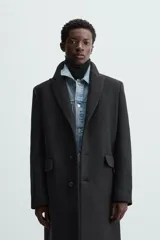Abrigo negro regular fit confeccionado en paño con lana. Tiene cuello con solapas de muesca, manga larga, bolsillos de solapa en la cadera, bolsillo interior, abertura en el centro de la espalda y cierre frontal con botonadura.