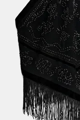 Top halter negro con cuello ajustable anudado, escote halter y hombros descubiertos. Presenta un panel central de terciopelo y apliques de abalorios brillantes en la parte delantera, con bajo asimétrico terminado en flecos largos.