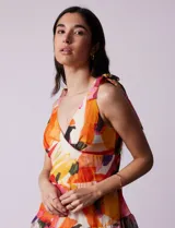 Vestido largo estampado de gasa, con escote en V, corte bajo el busto, lazos en los hombros, corte en la cintura, superposición de capas con volados, abertura central en la espalda con cierre invisible y forro interno a tono.