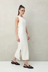 Vestido largo blanco de punto con textura acanalada, corte recto y aberturas laterales.