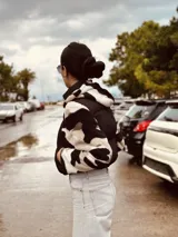 Campera puffer cropped negra con mangas y capucha de polar estampado con diseño geométrico en tonos beige, marrón y negro.