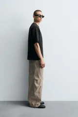 Pantalón de jean color marrón topo, de corte holgado y amplio en toda la pierna, con tiro medio, cinco bolsillos, efecto lavado, detalle de pinzas en perneras y cierre frontal con cremallera y botón.