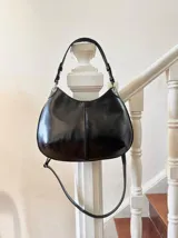 Cartera de cuero negra con doble correa desmontable, una corta y otra larga.