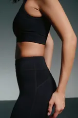 Calza deportiva negra, tiro alto, corte 7/8 y paneles de mesh en la parte inferior de la pierna.