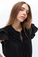 Blusa blanca de lyocell y algodón, con escote fruncido con volados y lazos.