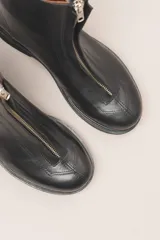 Bota corta de cuero color chocolate, con cierre central y suela de goma.