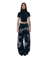 Pantalón unisex de denim 100% algodón con lavado overo (manchas grises sobre negro). Calce wide/relajado, tiro medio, pierna extra ancha y caída larga. Cintura con elásticos laterales, costuras curvas, bolsillos delanteros y traseros curvos, presillas para cinto, cierre y botón metálico.