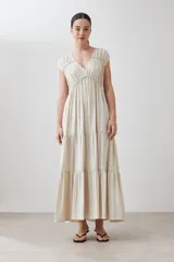 Maxi vestido color beige melange, con escote en V, mangas cortas y falda larga con volantes.