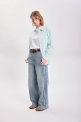 Pantalón jean celeste de corte ancho con detalle de franja lateral azul oscuro.