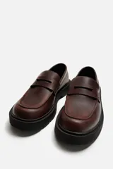 Mocasín de cuero color marrón oscuro, con antifaz y suela track de goma negra.