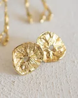 Aros tipo botón dorados con textura irregular que simula la superficie de un molusco.