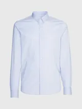 Camisa celeste de popelín de algodón elástico, corte slim, con cierre frontal de botones, mangas largas y monograma de Calvin Klein bordado en el pecho.
