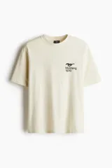 Remera color crema de corte holgado con estampado de un caballo Mustang y el año 1970 en el pecho. Cuello redondo con ribete fino y hombros caídos.