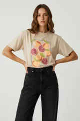 Remera color beige de algodón con estampado de frutas enmarcadas en un rectángulo de puntos.
