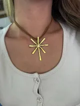 Collar con dije de bronce en forma de estrella de ocho puntas y cordón de cuero sintético marrón.