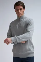 Buzo de punto gris claro melange con cuello alto y medio cierre.