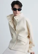 Chaqueta color crema de mezcla de lana con cuello alto y cierre de botones oculto.