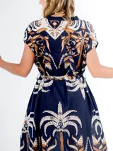 Vestido midi de algodón italiano, color azul marino con estampado en tonos blanco, beige y naranja/marrón. Presenta mangas cortas tipo murciélago, cuello en V con botones frontales y lazo desmontable para ajustar a la cintura.