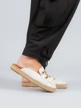 Sandalia mule color blanco con aplique metálico dorado y suela de yute.