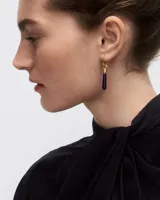 Aro individual dorado con dije colgante de piedra azul en forma de gota.