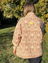 Chaqueta acolchada con estampado ikat en tonos beige y marrón, de corte holgado y cuello mao.