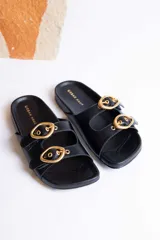 Sandalias de cuero color beige con dos tiras anchas y hebillas doradas ajustables.