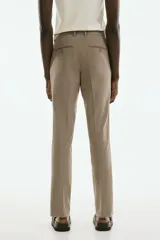 Pantalón de vestir color beige, corte slim fit, con cierre de botón, bolsillos laterales y bolsillos traseros ribeteados con botón.