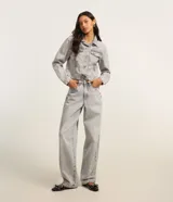 Pantalón baggy de jeans color gris claro, con trabillas en la cintura, cierre tradicional y bolsillos.
