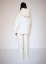 Campera puffer color crema con capucha, cierre frontal con botones a presión y bolsillos laterales.