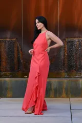 Vestido largo color coral, con escote halter, espalda descubierta y volados en la falda.