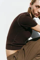 Top de punto color marrón con cuello redondo y manga corta. Detalle de ribete blanco en cuello y mangas.