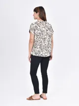 Camisa de manga corta con estampado animal print en tonos beige, marrón y negro. Tiene cuello mao y cierre frontal con botones.