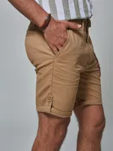 Bermuda color beige con cinturón, corte regular fit, dos bolsillos delanteros, dos traseros, un bolsillo relojero y botamanga con presilla. Aplique de badana.