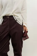 Pantalón de jean azul oscuro de corte recto con detalle de botones dorados en el tobillo.