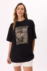 Remera color beige de corte amplio con mangas cortas y cuello redondo. Estampado frontal con la palabra "Monaco" en la parte superior y una fotografía en blanco y negro con la frase "Mont Carlo" en la parte inferior.