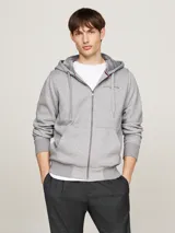 Buzo gris con capucha Tommy Hilfiger, con cierre de cremallera, bolsillos tipo canguro, forro de piel sintética y logo bordado en el pecho.