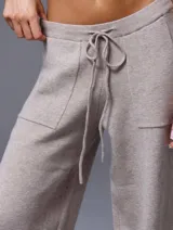 Conjunto de chaleco corto de punto con botones y pantalón de punto con bolsillos grandes y lazo en la cintura, color beige.
