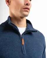 Sweater verde de punto con cuello alto y cierre medio con cremallera.