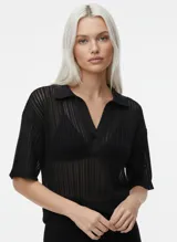 Remera negra oversize con cuello tipo polo y mangas cortas con hombros caídos. Confeccionada en punto single jersey con mezcla de algodón, algodón reciclado y poliéster reciclado. Silueta amplia y relajada.