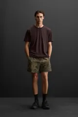 Camiseta deportiva marrón de tejido técnico ligero y elástico con estructura. Cuello redondo, manga corta, costuras planas y logo estampado.