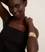Pulsera rígida dorada con textura martillada y forma orgánica.