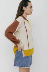 Sweater de punto color verde esmeralda, con cuello polo, mangas largas color crema y detalles en rosa.